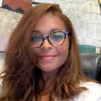 Felicia facing forward, smiling, long red hair, beige shirt