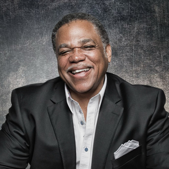 Terence is facing forward and smiling. He has dark, graying hair and wears a black shirt.