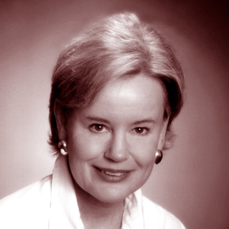 Marilyn Archer facing forward and smiling. She has short hair and wears earrings and a light shirt.