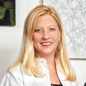 Cathy is facing forward and smiling. She has long blonde hair and wears a white shirt.