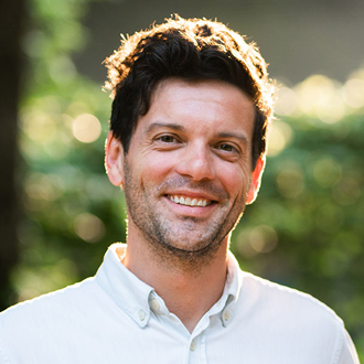 Trey is facing forward and smiling. He has short brown hair and wears a white shirt.