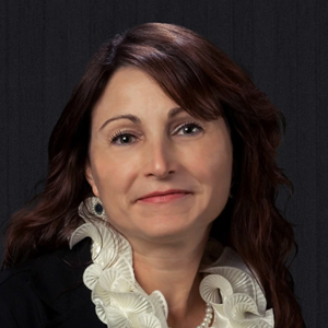 Rebecca Barham smiling at the camera, long brown hair, dark jacket and white blouse with ruffles