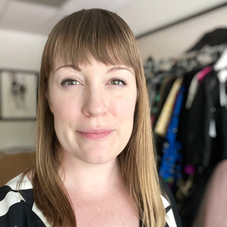 Annette Becker, brown hair, clothes on hangers behind her.