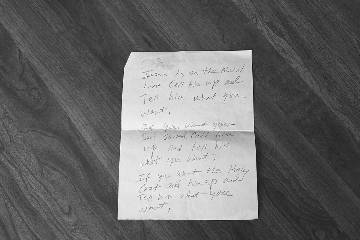 Black-and-white photograph of a handwritten note on a piece of white paper. 