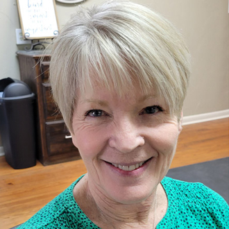 Mary Braden smiling, short blonde hair, green top