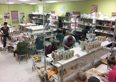 CVAD Ceramics studio with students at work and projects on the tables and shelves