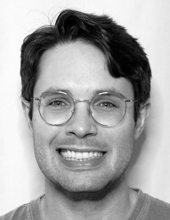 Terry Davis smiling at the camera, black and white, wearing glasses
