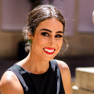 Xenia smiling, hair pulled back, black sleeveless top