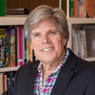 Professor Michael Gibson facing forward, smiling, books in the background