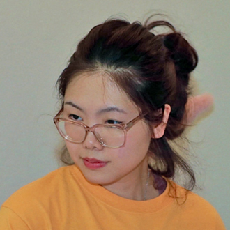 Jingfei looking to her right, black hair, glasses, orange top