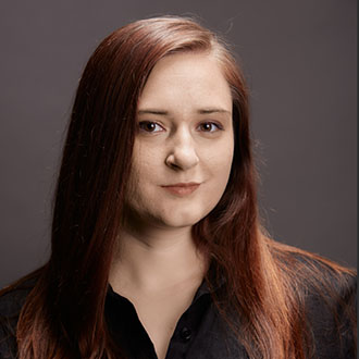 Allison facing forward smiling, long brown hair, dark-colored shirt.