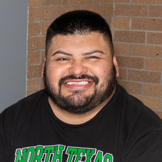Erasmo Rodriguez facing forward, smiling, dark hair, mustache and beard, black North Texas t-shirt