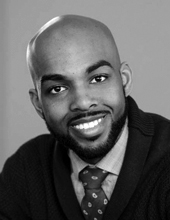 Omari Souza looking at the camera, smiling, wearing a tie